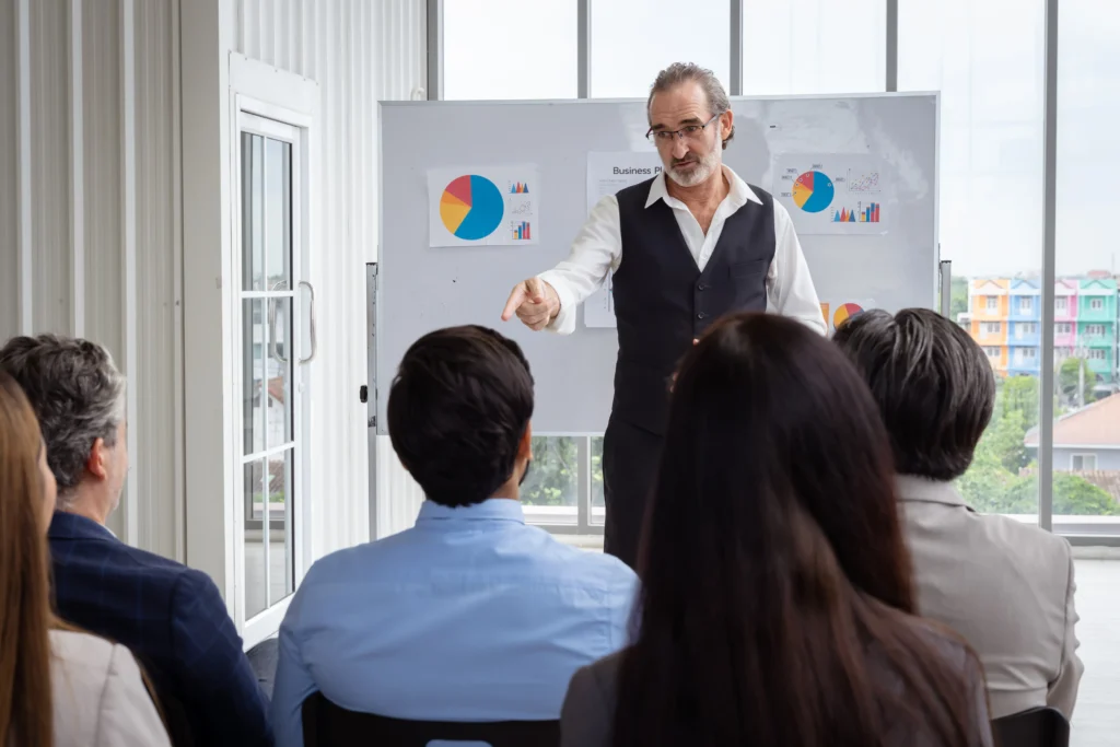 Capacitador señala un gráfico, el momento captura la atención durante una sesión de capacitación y desarrollo del personal.