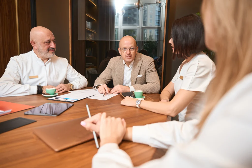 Tres ejecutivos en una sesión de asesoría empresarial discuten con enfoque y claridad los planes y objetivos futuros.