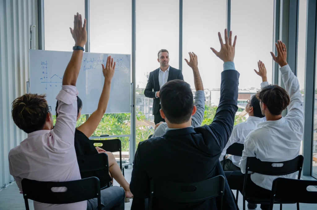 Experto interactúa con empleados en una sala, la participación subraya el valor de la capacitación y desarrollo del personal.