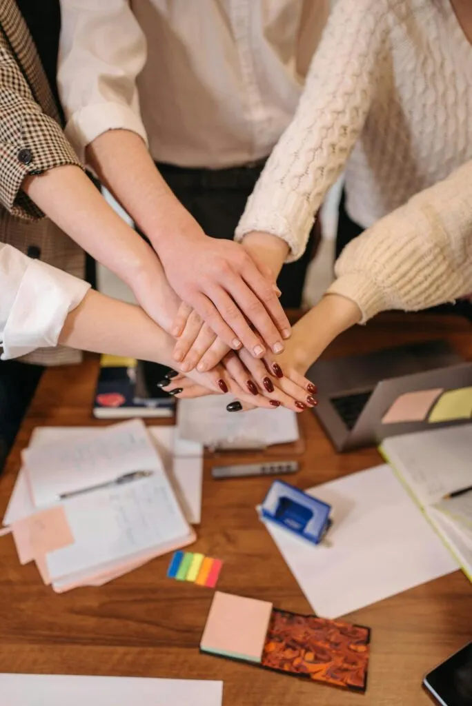 Esta imagen captura un momento de unidad y colaboración. Las manos de un equipo se apilan, una sobre otra, simbolizando la fuerza y el apoyo mutuo que se logra a través de una sólida gestión de recursos humanos.