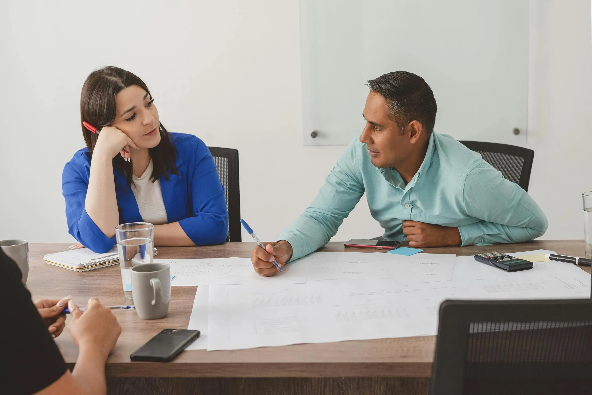 Sesión de diagnóstico: qué es la consultoría empresarial y su proceso Equipo de trabajo analizando gráficos y planos sobre una mesa de madera para entender qué es la consultoría empresarial estratégica.