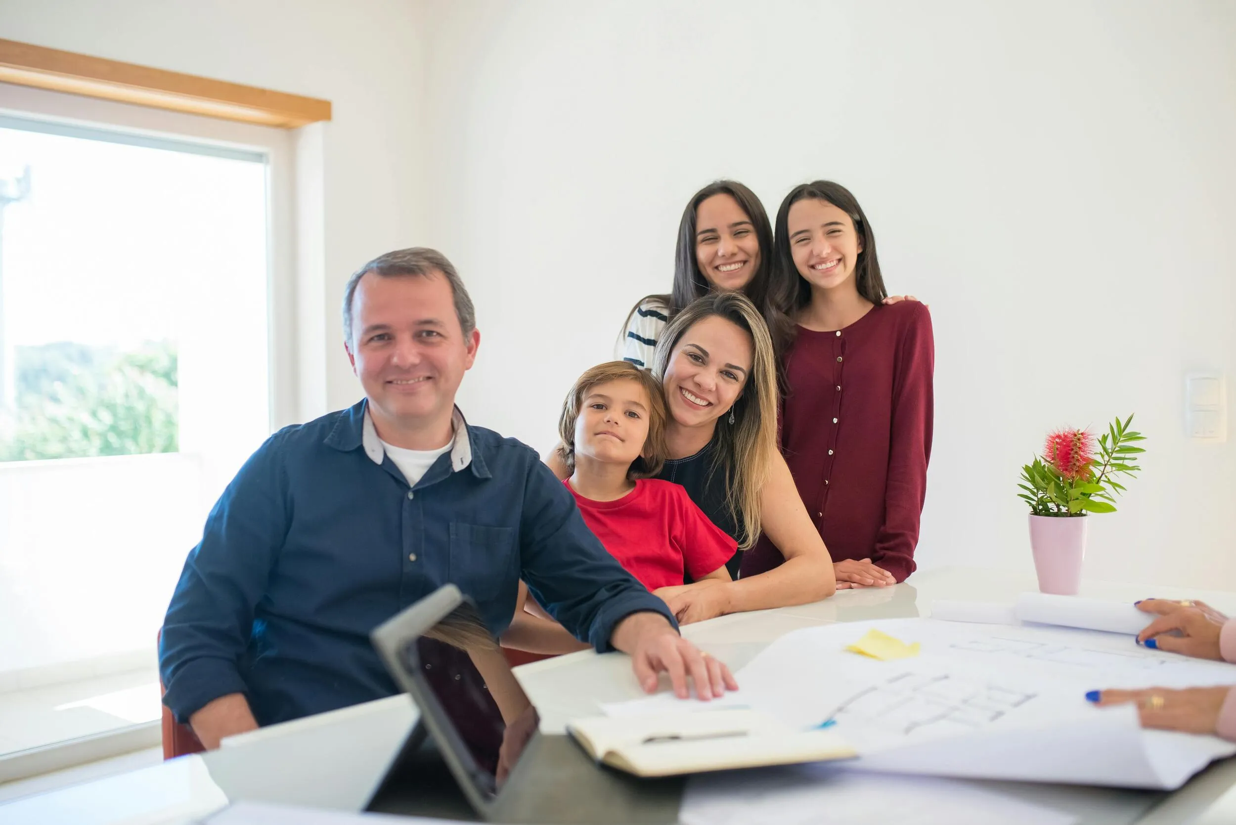 Una familia unida sonriendo junto a planos de un proyecto, representando el beneficio del protocolo familiar en empresas familiares.